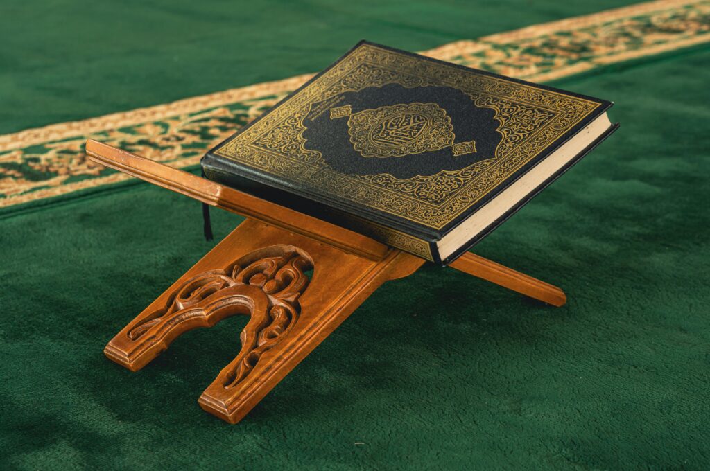 Quran placed on a beautifully carved wooden rehal inside a mosque.